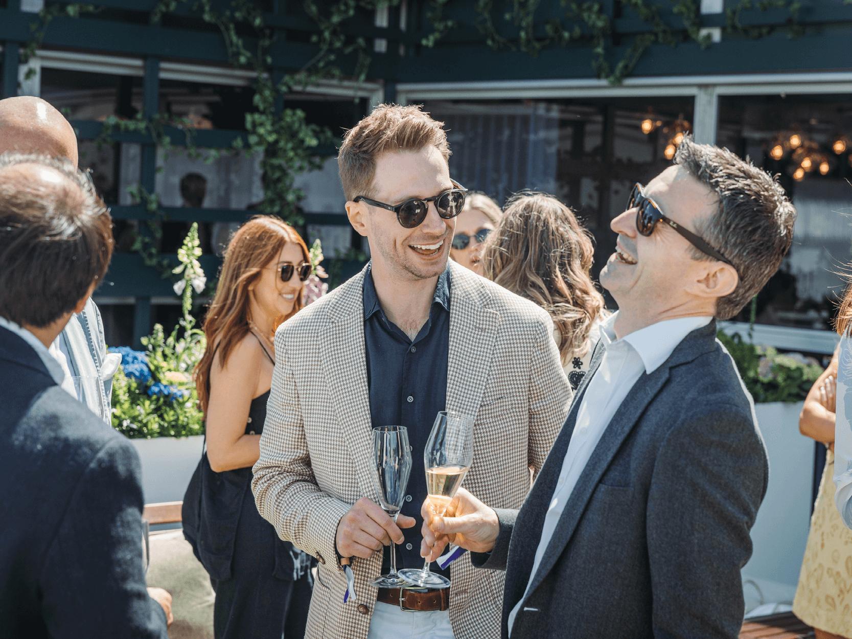 Guests in the Rosewater Pavilion garden at Wimbledon smiling and chatting before watching the tennis