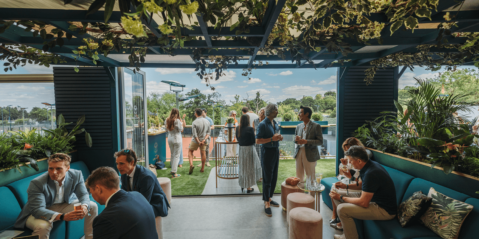View of the seating area with guests chatting and balcony in The Treehouse hospitality at The Championships, Wimbledon