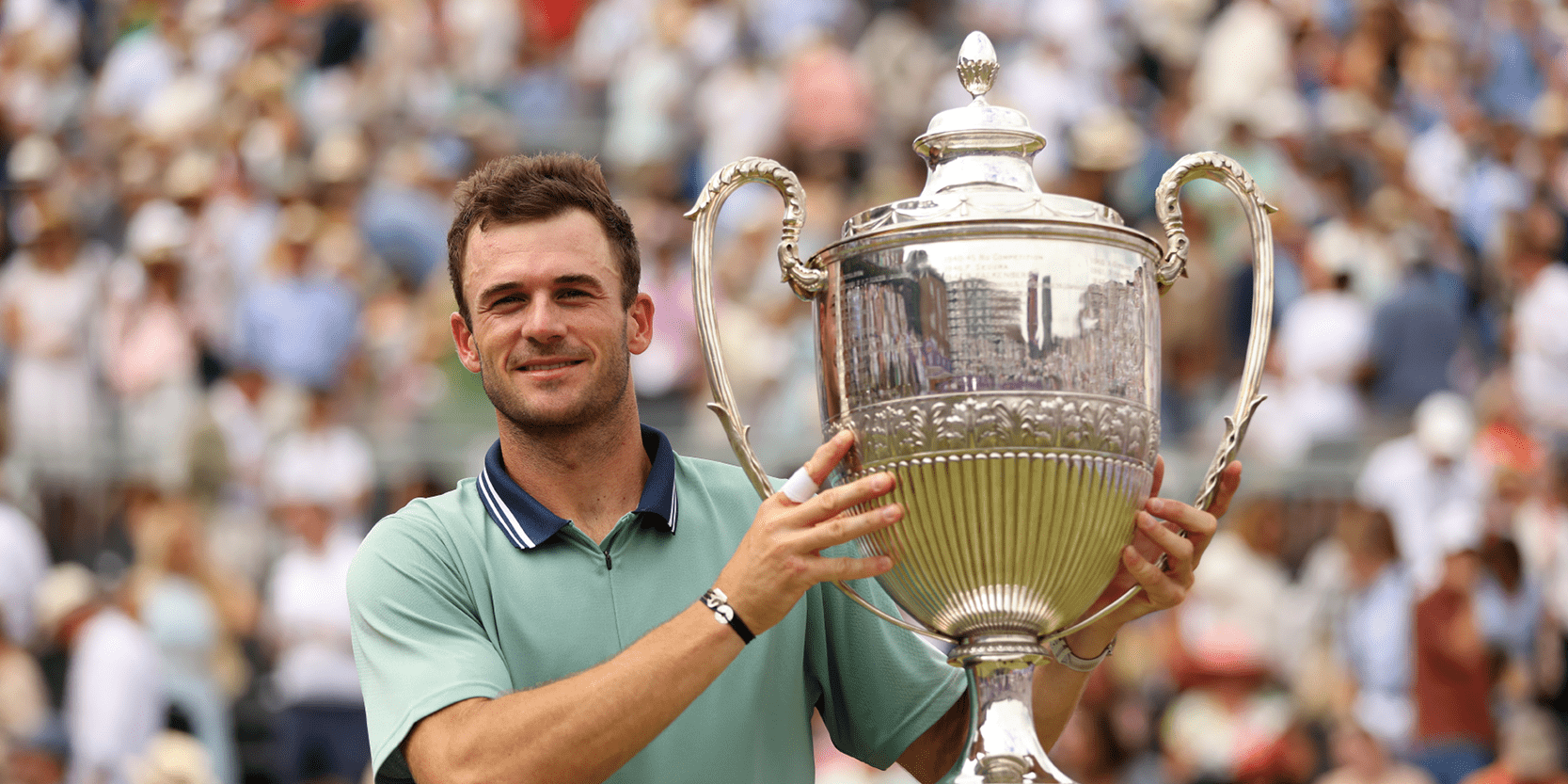 American tennis player Tommy Paul holding The Queen's Club Championships trophy after winning the final of 2024 on Centre Court
