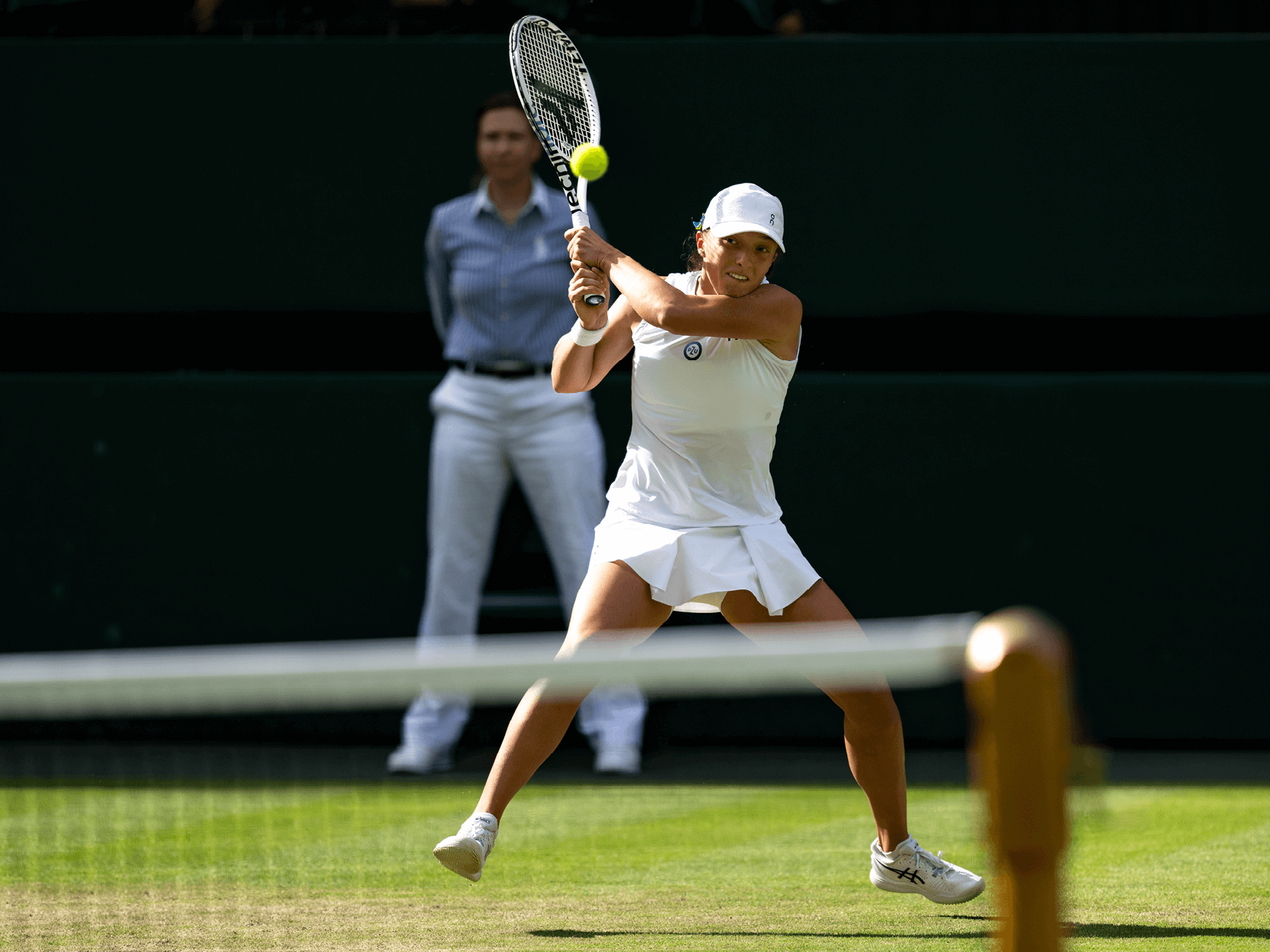 Women's tennis player Iga Swiatek hitting a backhand on Centre Court at Wimbledon in 2023