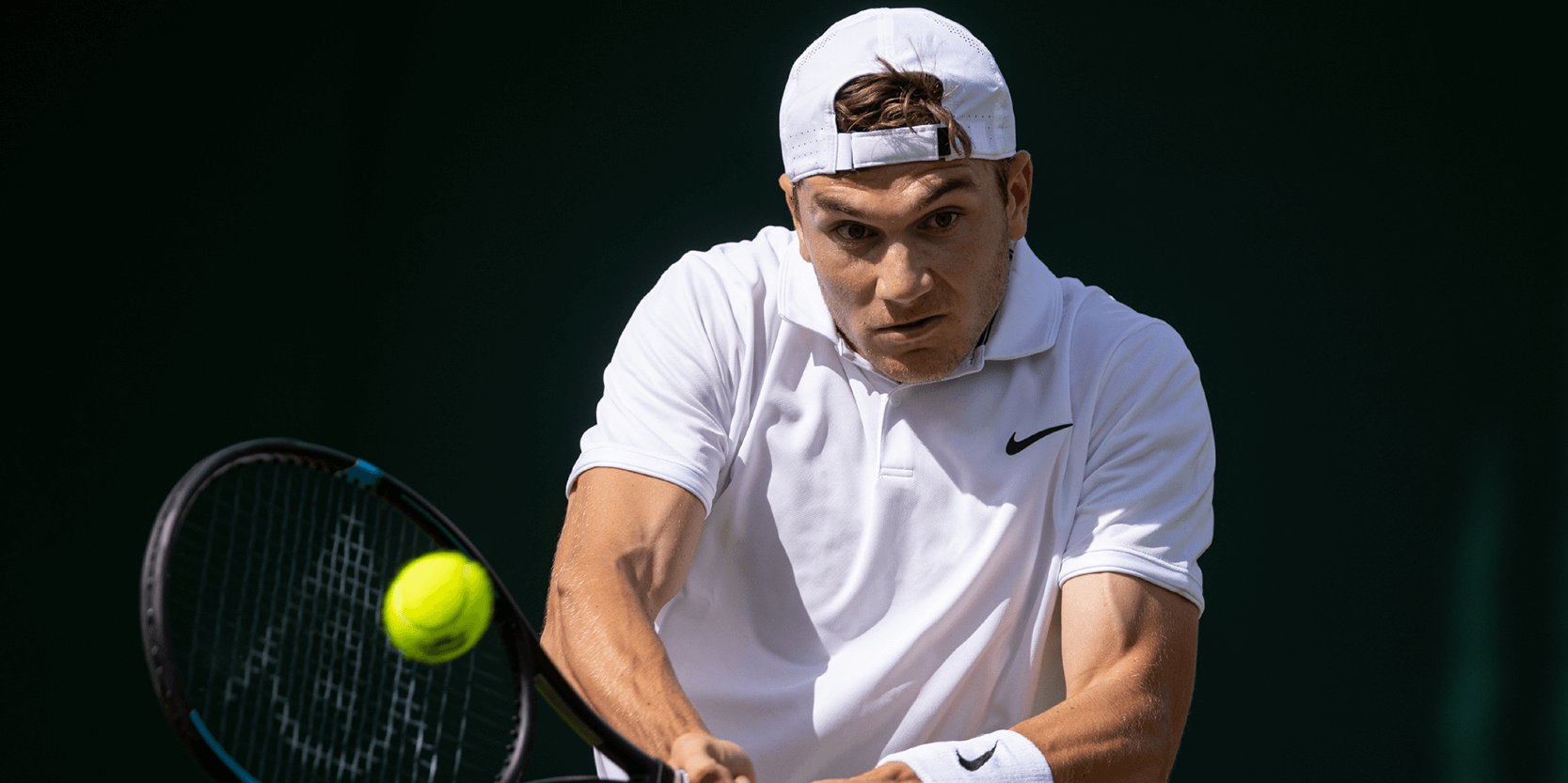 British tennis player Jack Draper hitting the ball in a match on Centre Court at Wimbledon