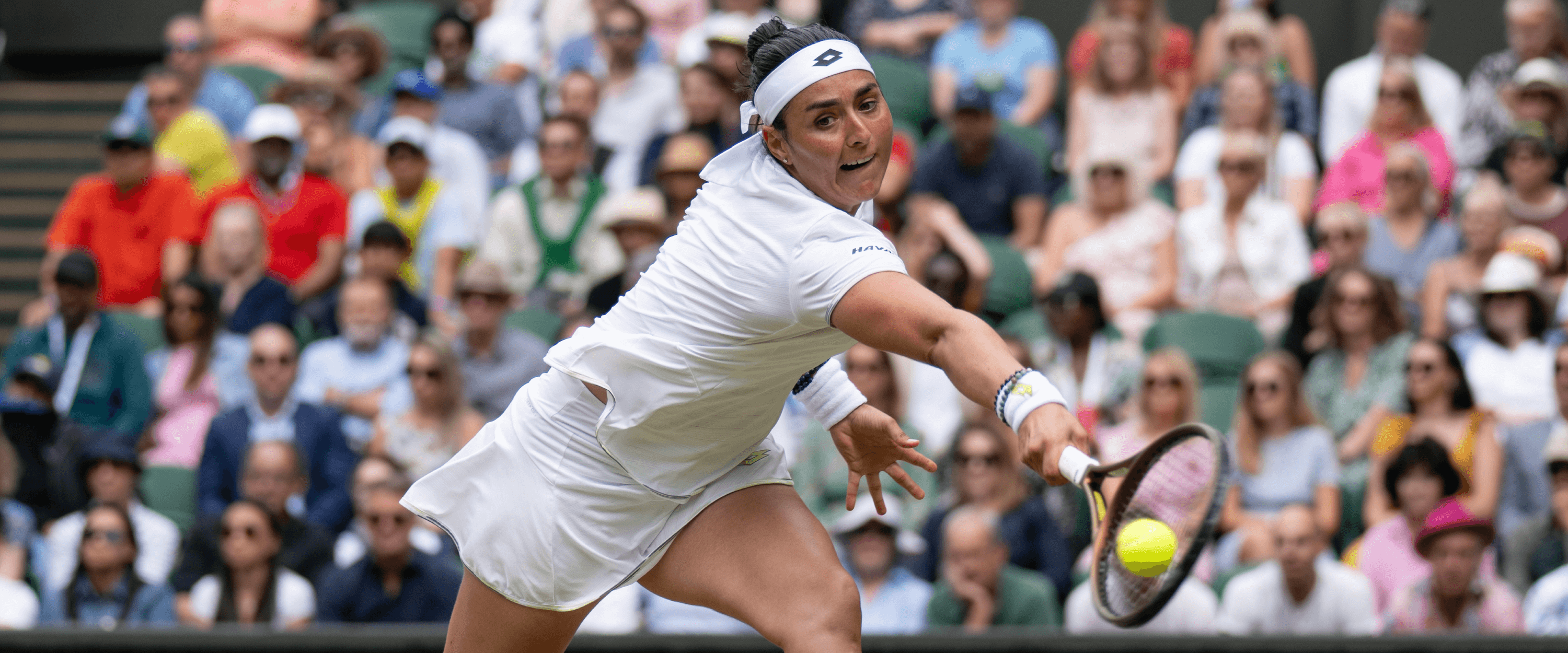 Women's tennis player Ons Jabeur reaching for the ball to hit a return shot during The Championships Wimbledon tennis grand slam tournament 
