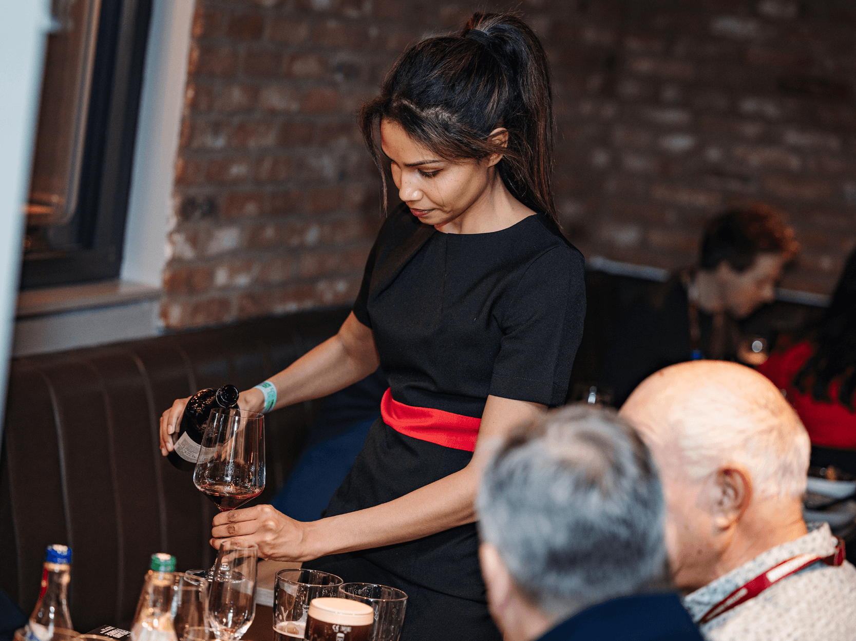 Hostess in The Gate hospitality at Allianz Stadium pouring a glass of wine for guests at a rugby match