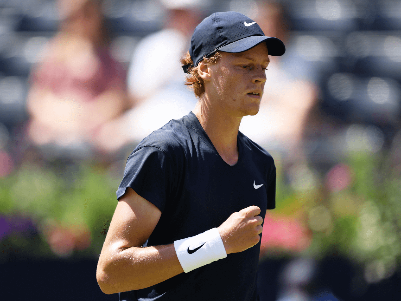 Men's tennis player Jannik Sinner gripping his fist in celebration during the Queen's Club Championships in London