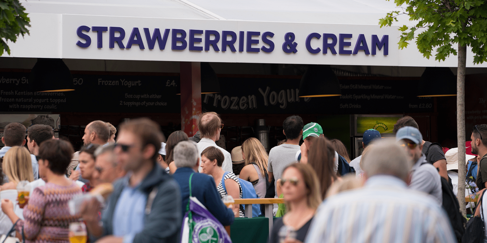 Strawberries and cream stand inside the ground at Wimbledon tennis tournament with queues of fans lining up to buy them