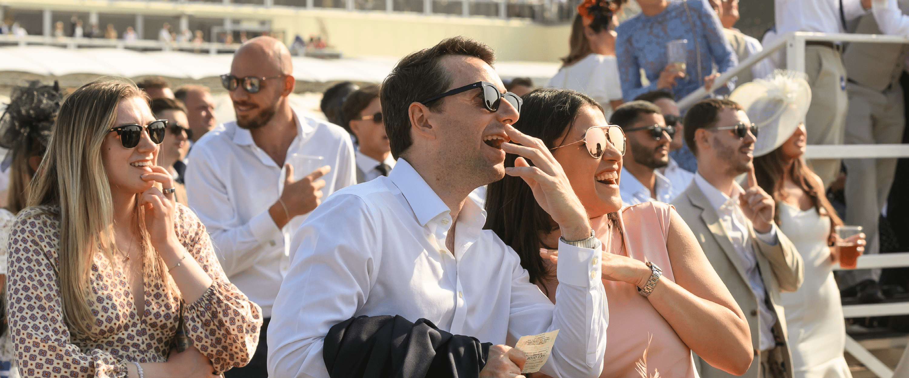 Guests smiling and eagerly watching and reacting to a race at Royal Ascot