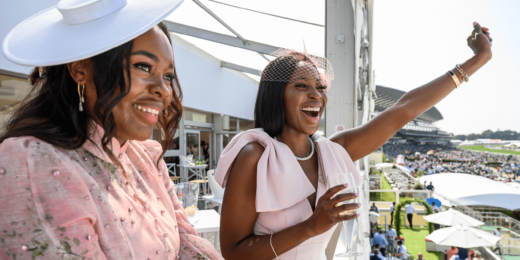 Ladies cheering from a viewing balcony at Royal Ascot during a race