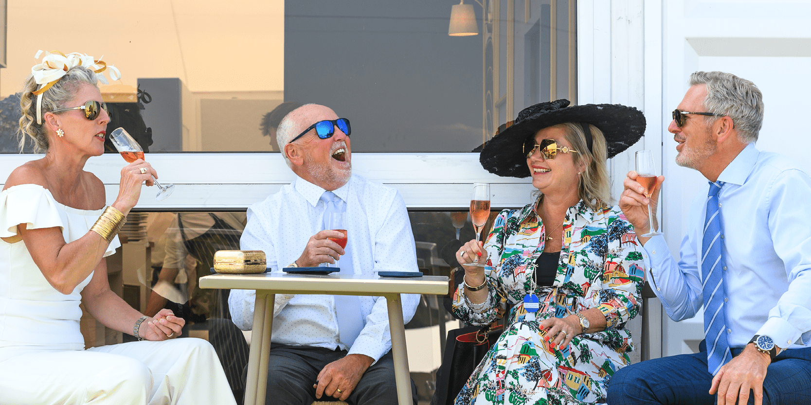 Guests smiling and laughing over a glass of Champagne in hospitality at Royal Ascot