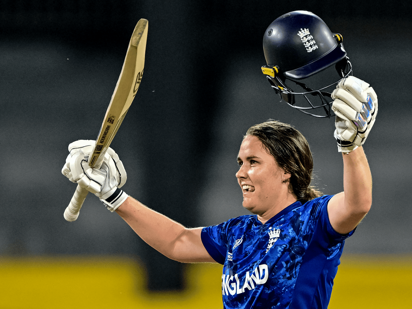 England women's cricket player Nat Sciver-Brunt holding her bat in the air after a victory