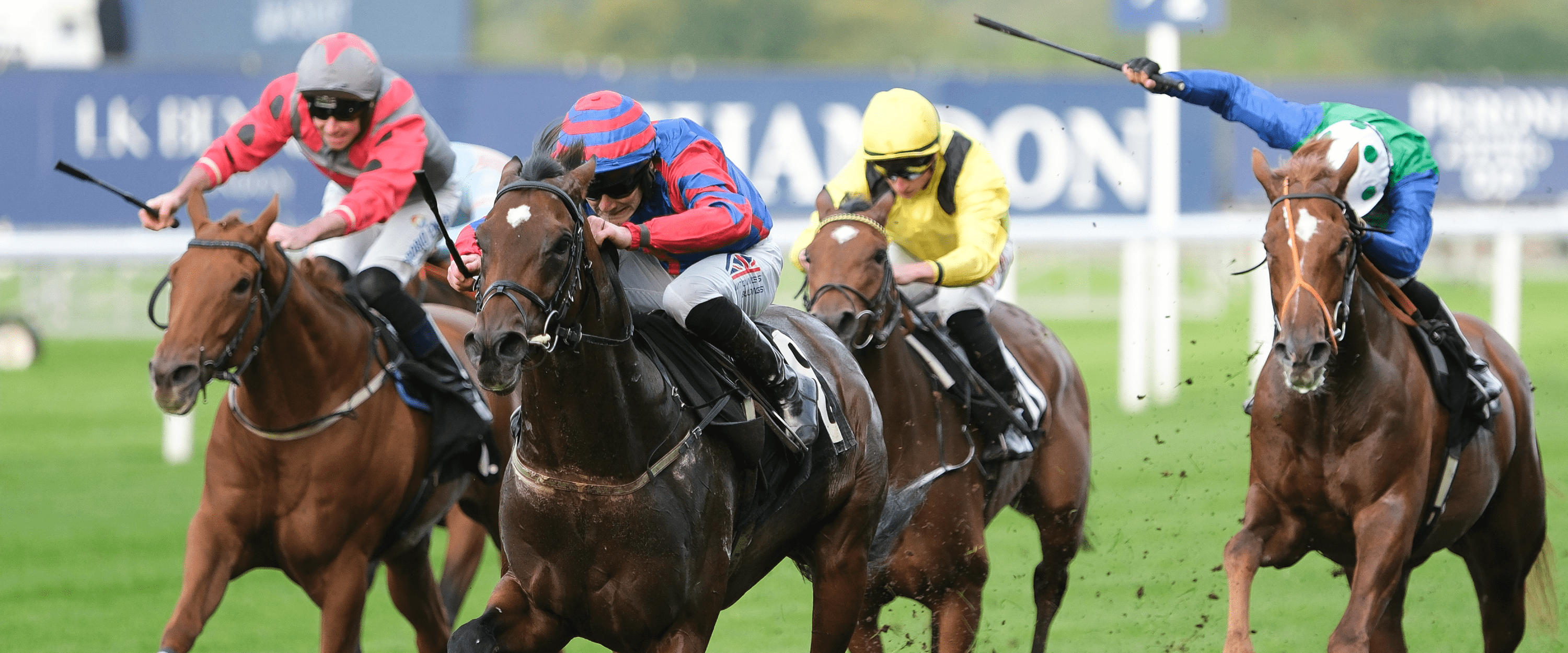 Jockeys racing and horses jumping during a race at Ascot Racecourse in England