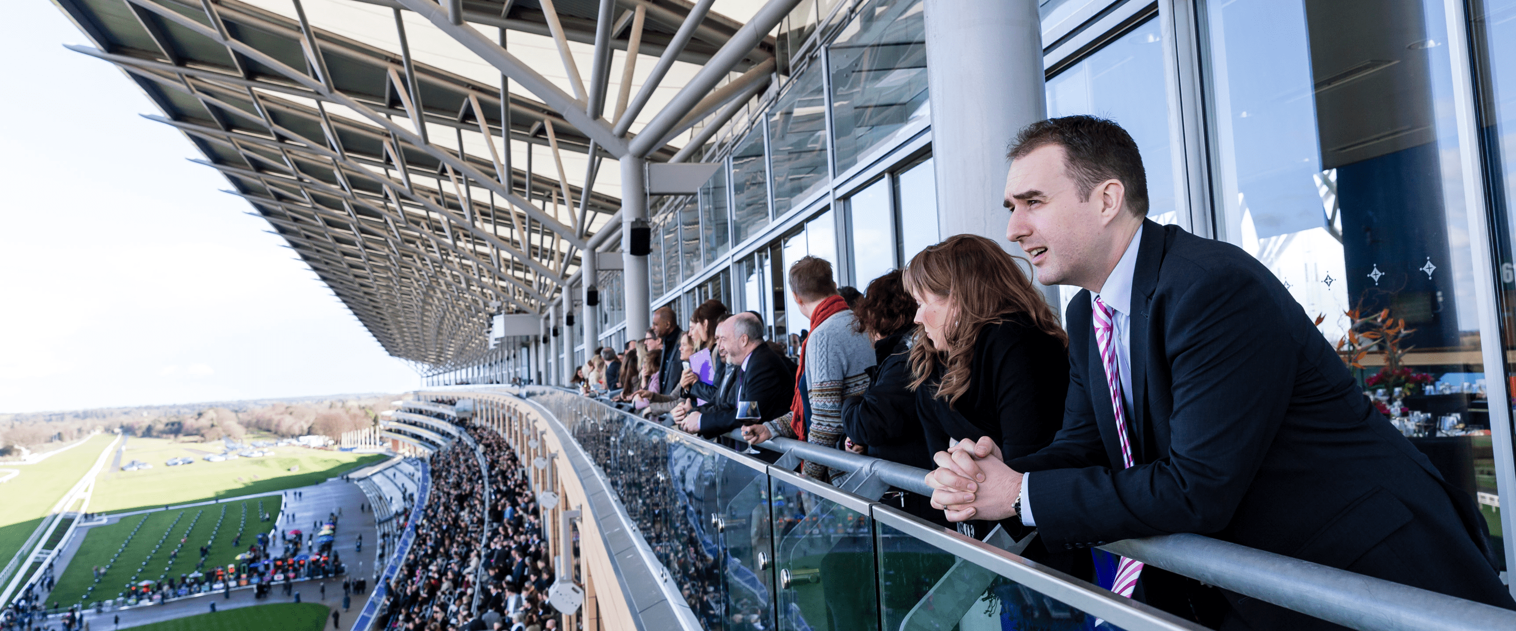 Guests on the balcony in the hospitality enclosure at Royal Ascot watching the horse racing on the home straight
