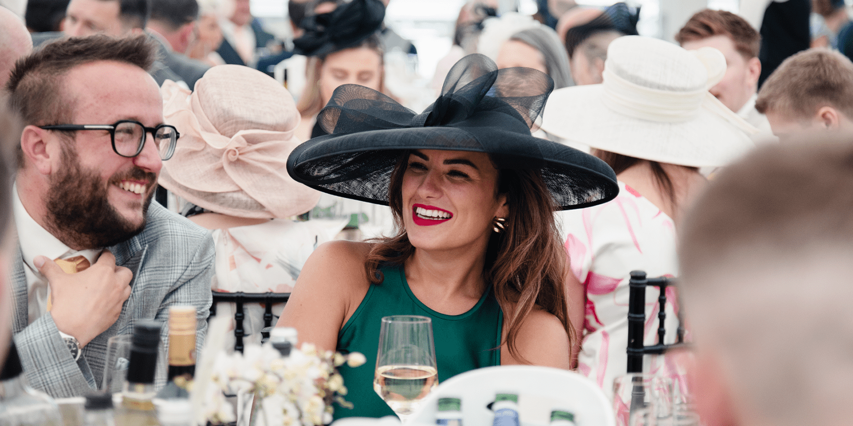 Man and lady smiling whilst sat down at their table at Royal Ascot horse racing event 