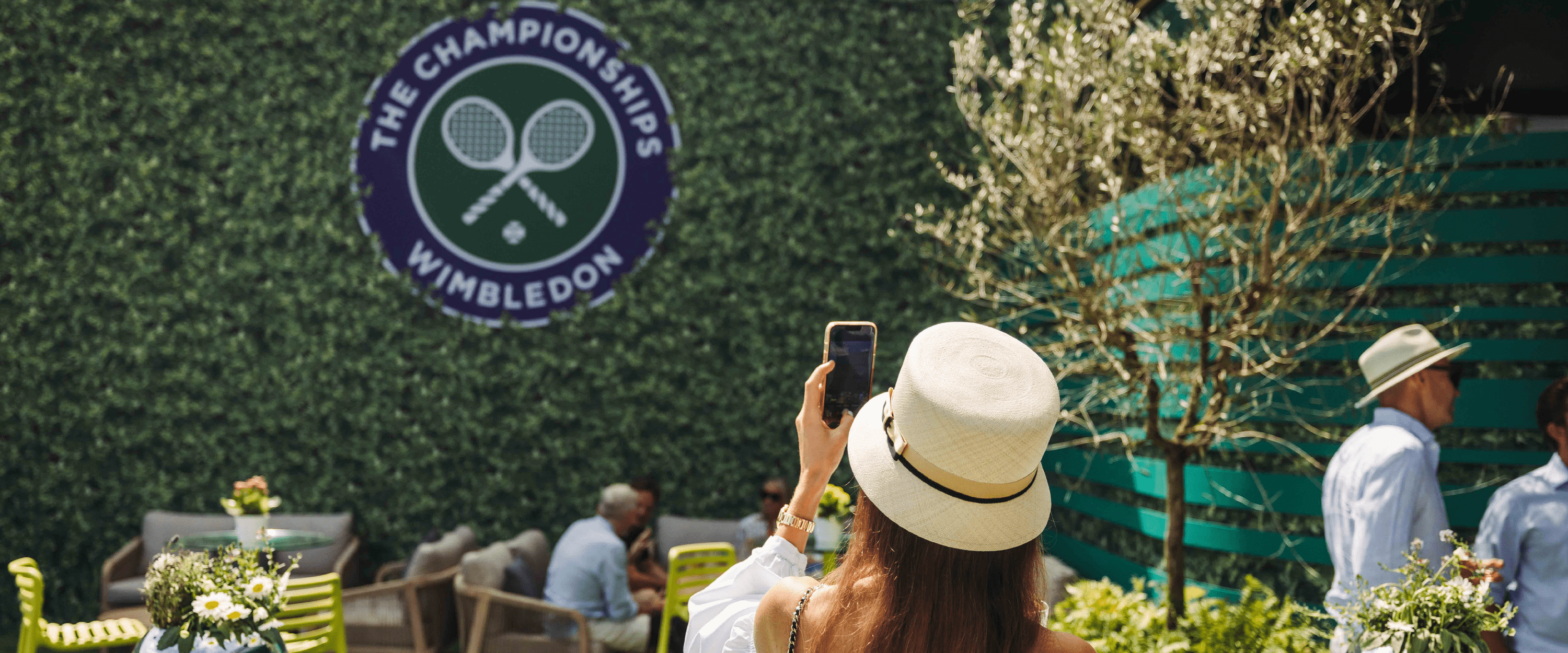 Guest in hospitality at Wimbledon in The Lawn taking a photo of the Wimbledon logo in the garden