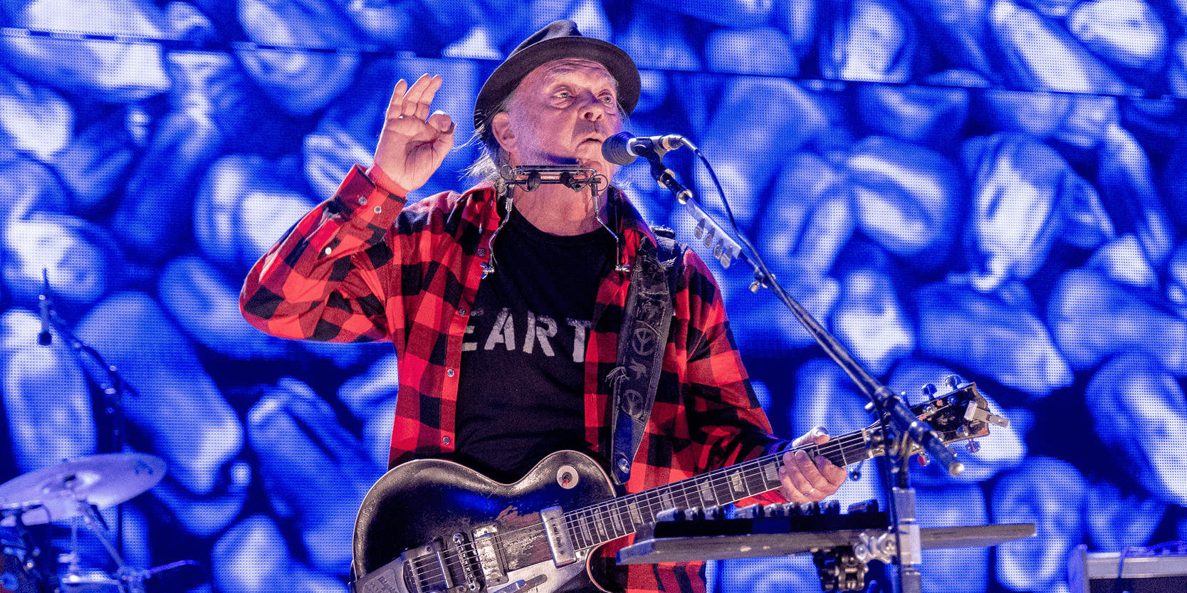 Rock and country music legend Neil Young performing on stage with his guitar