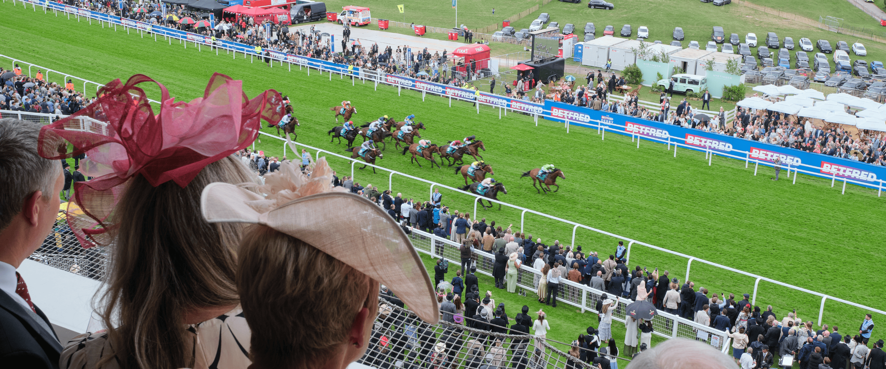 View of the racetrack and the horses racing down the finishing straight from a hospitality suite at Epsom Downs Racecourse for the Epsom Derby Festival