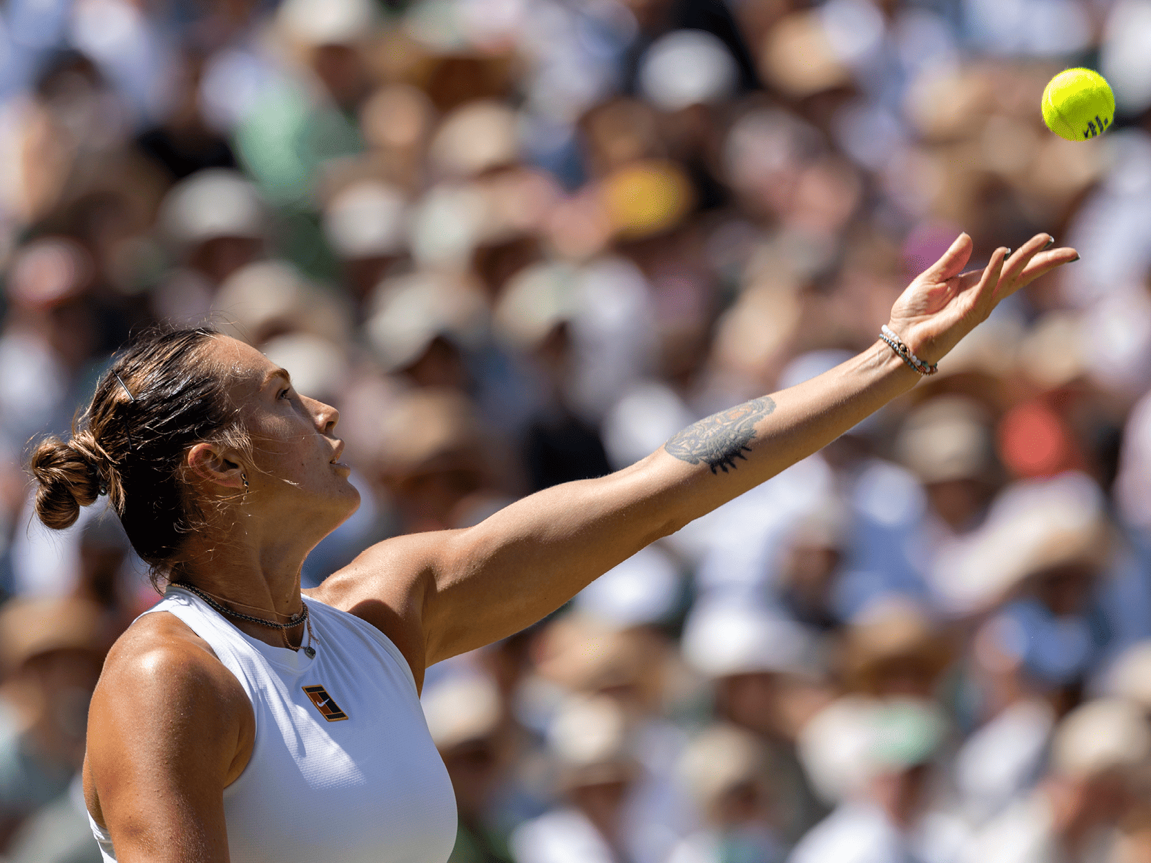 Women's tennis player Aryna Sabalenka serving during a match at Wimbledon in 2025