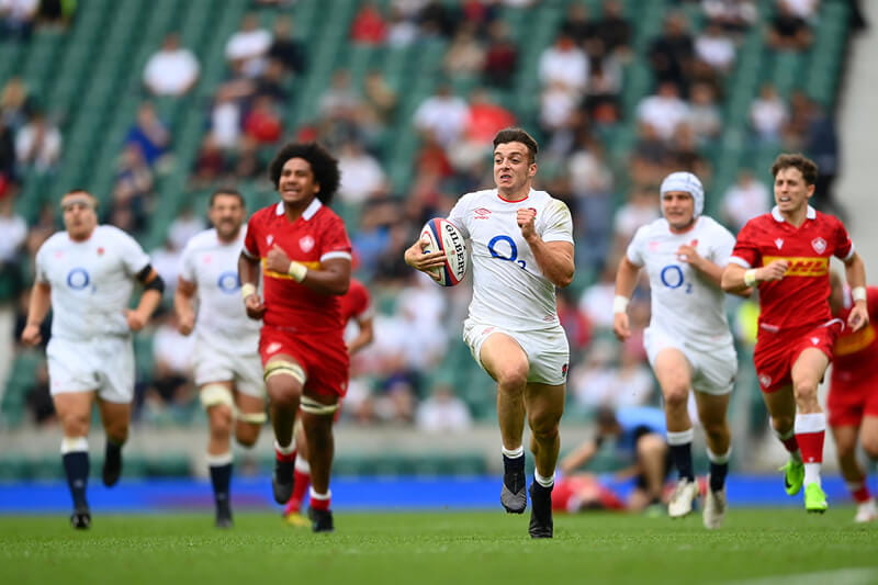 Adam Radwan running with the ball in an England rugby match at Twickenham Stadium
