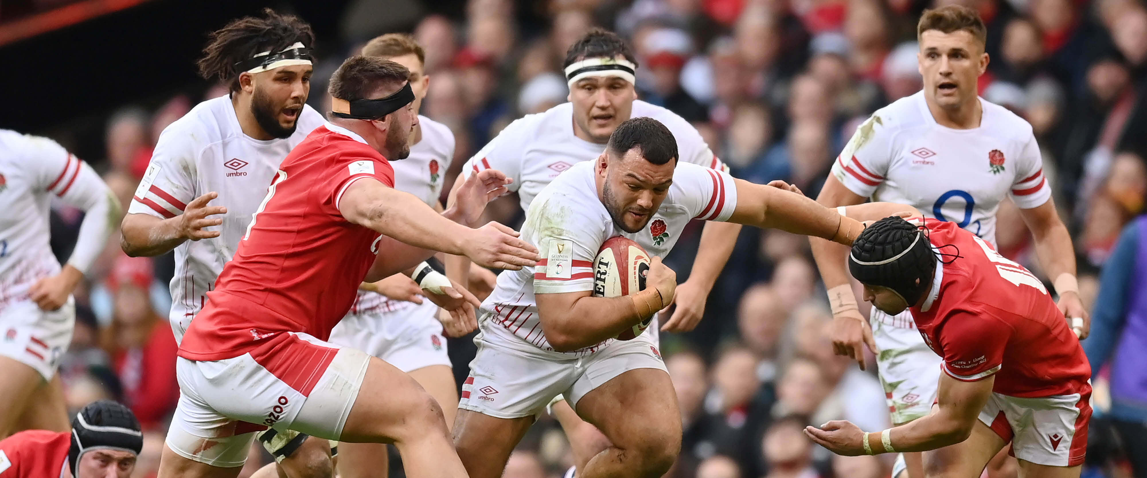 England rugby player Ellis Genge running with the ball in a match against Wales in the 2023 Guinness Six Nations to score a point, fighting off his opponents