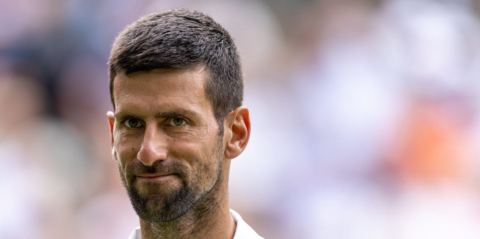 Tennis player Novak Djokovic smiling during a match on Centre Court at Wimbledon