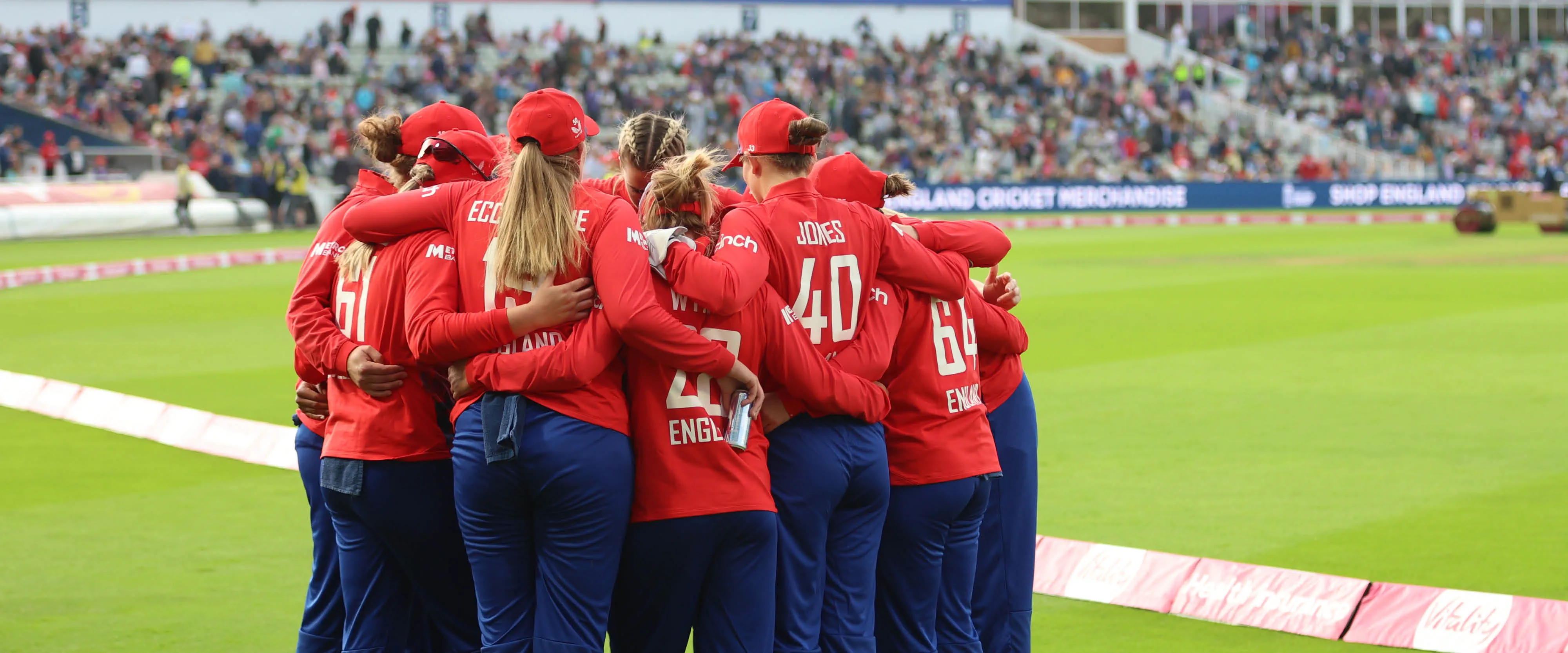 Women's England IT20 team hugging on pitch