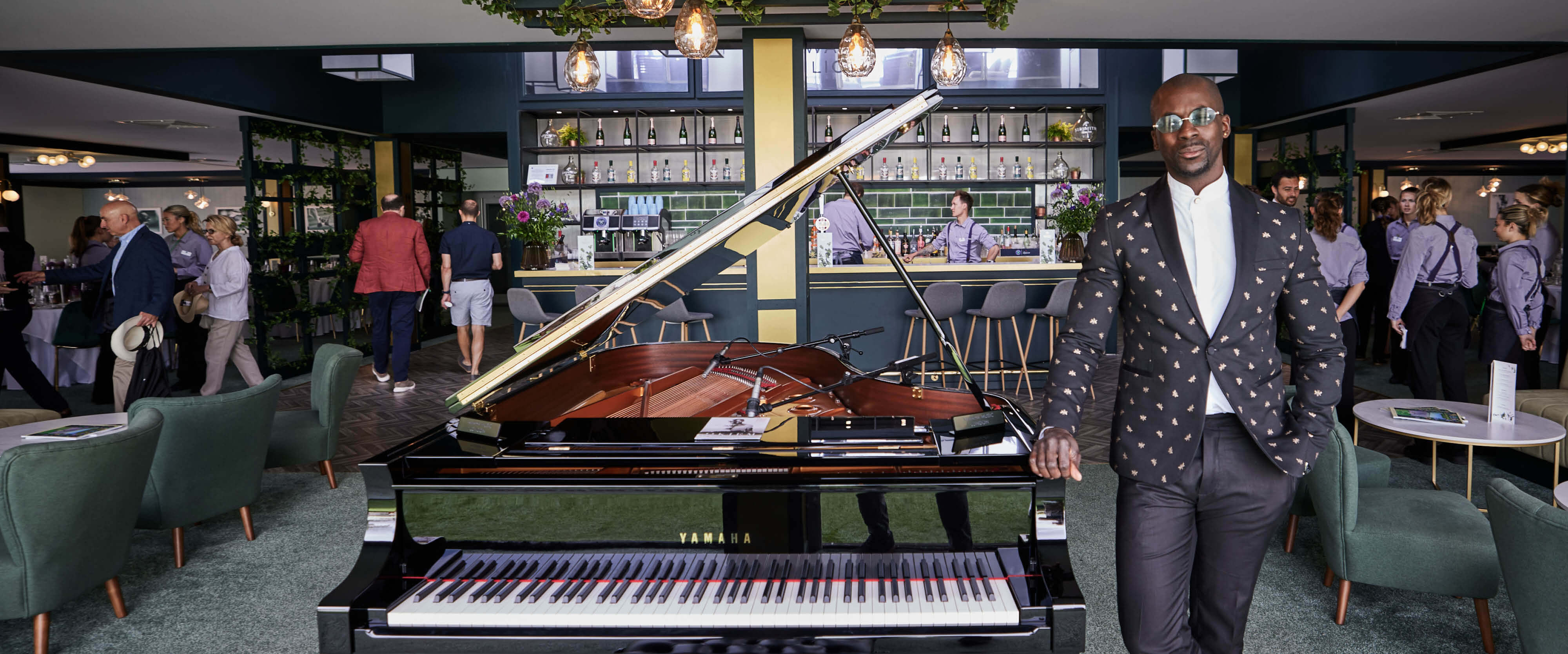 Pianist Okiem smiling for a photo with his piano inside Rosewater Pavilion hospitality facility playing for guests at The Championships Wimbledon
